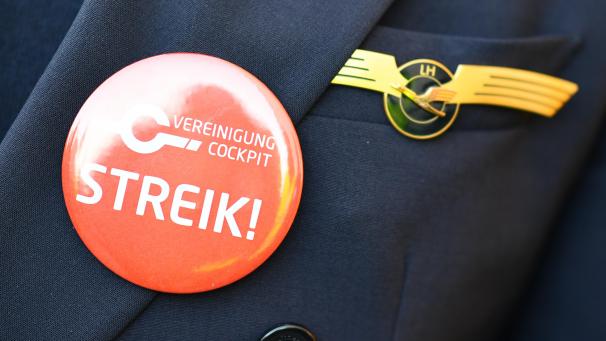 <p>Ein Lufthansa-Pilot trägt einen Button mit der Aufschrift „Streik“ auf seiner Uniform.</p>