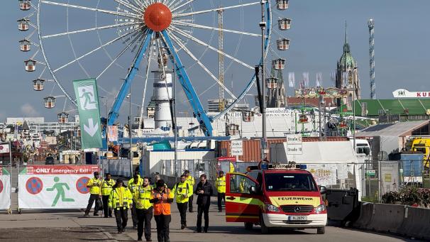<p>Sicherheitskräfte und Einsatzkräfte der Feuerwehr stehen vor dem Gelände vom Oktoberfest</p>