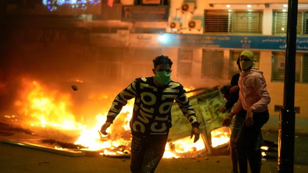 <p>Personen stehen neben einem abgefackelten Polizeifahrzeug, als die von Jugendlichen angeführten Proteste für Reformen im Gesundheits- und Bildungswesen in Gewalt umschlugen.</p>
