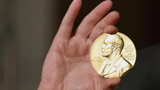 <p>Eine Nobelmedaille wird während einer Zeremonie in New York hochgehalten.</p>