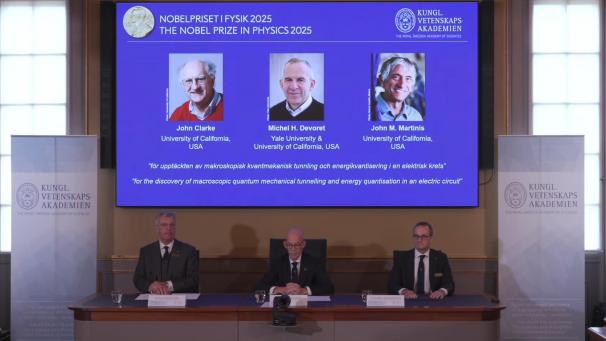 <p>Standbild aus dem Livestream zur Bekanntgabe des Nobelpreises für Physik 2025: Auf einer Leinwand ist die Präsentation der diesjährigen Preisträger, die in den USA forschenden Quantenphysiker John Clarke (l-r), Michel Devoret und John Martinis, zu sehen.</p>