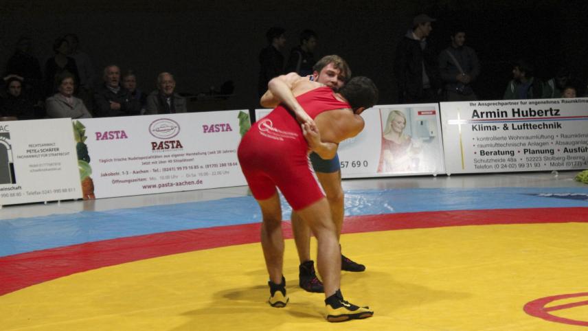 <p>Das Bild zeigt Georgiy Mizilin (hinten, im blauen Kampfanzug), in der Umklammerung, aus der heraus er seinen Gegner angriff.</p>