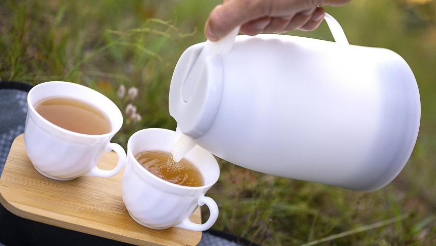 <p>Ein Mann gießt bei einem Picknick warmen Tee aus einer Thermoskanne in eine Tasse. Vor 120 Jahren trat die Thermosflasche ihren internationalen Siegeszug an.</p>