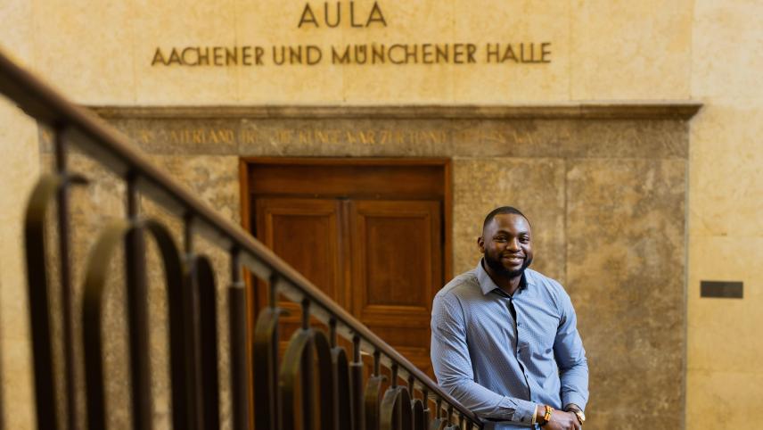 <p>Contimi Kenfack Mouafo, Student der Elektrotechnik an der RWTH Aachen, steht in einem Universitätsgebäude. Der 28-Jährige engagiert sich mit dem Verein „3 E’s 4 Africa“.</p>
