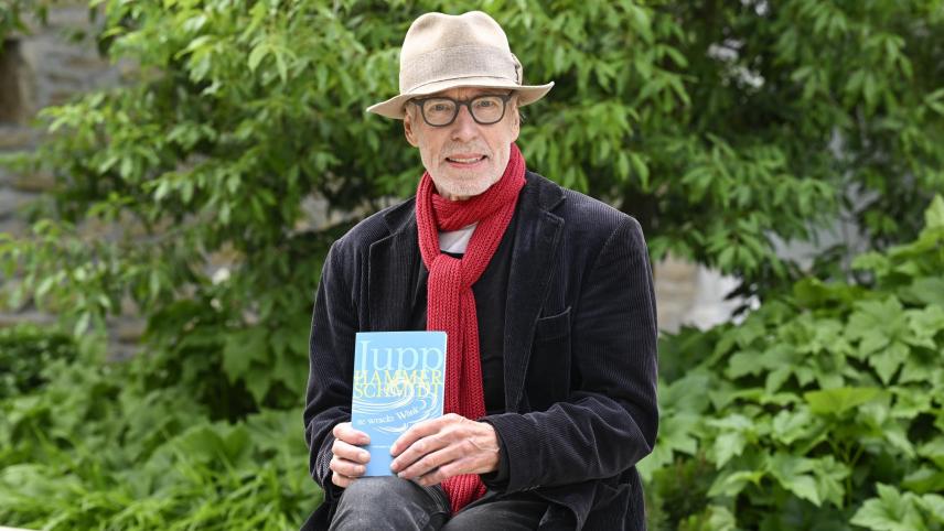 <p>Jupp Hammerschmidt vor dem Verlagsgebäude von GE-Media in Eupen mit seinem neuen Buch „ne wracke Wönk“. Darin blickt der Autor auf die Eifel seiner Kindheit und Jugend zurück – von Kaffeeschmuggel und Narzissenwiesen bis zur legendären Beatmesse.</p>
